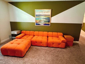 A sectional sofa in a room with a green and white wall, a small side table, and a framed picture.