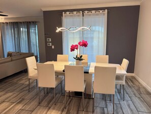 Un espace repas comprenant une table, des chaises et un luminaire suspendu au design moderne.