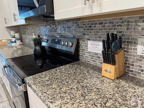 A kitchen with a granite countertop, stainless steel stove, and a knife block. - Modern 6BR Villa Kissimmee | Perfect for 14 Guests (Kissimmee)