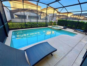 Une piscine dotée d’une structure en verre, de chaises longues et d’un jacuzzi.