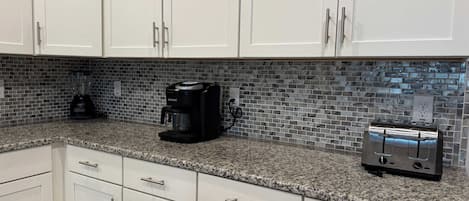 Una cocina con armarios blancos, una cafetera y un tostador sobre la encimera.