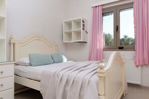A bedroom with a bed, a dresser, a window with curtains, and a white cabinet. - Astarte Villas - Stilvi 4 Bedroom Private Villa With Pool (RV3V+9Q3 Zakynthos, Greece)