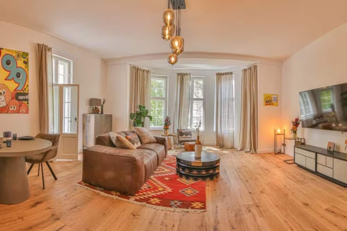 Ein geräumiges Wohnzimmer mit einem braunen Ledersofa, einem runden Couchtisch und einem Fernseher an der Wand.