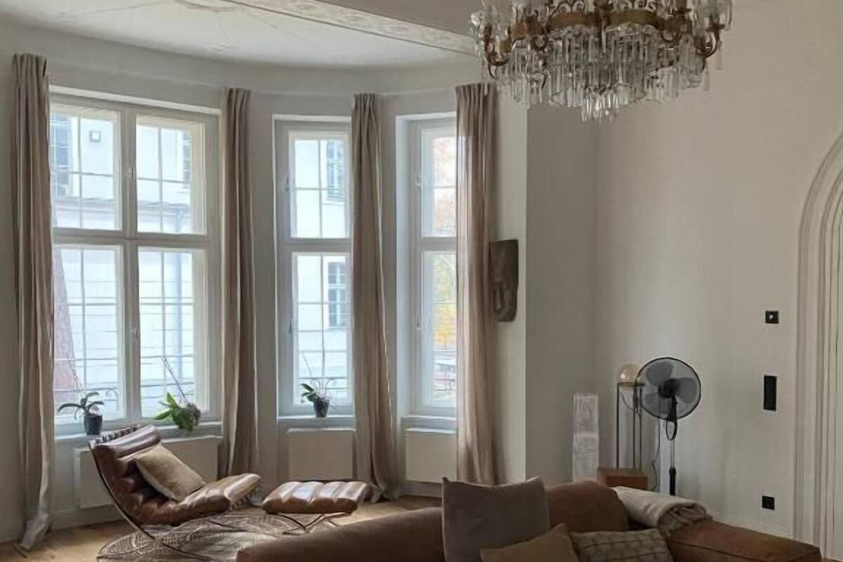 Ein Wohnzimmer mit einem braunen Ledersofa, einem runden Couchtisch und einer Deckenleuchte.