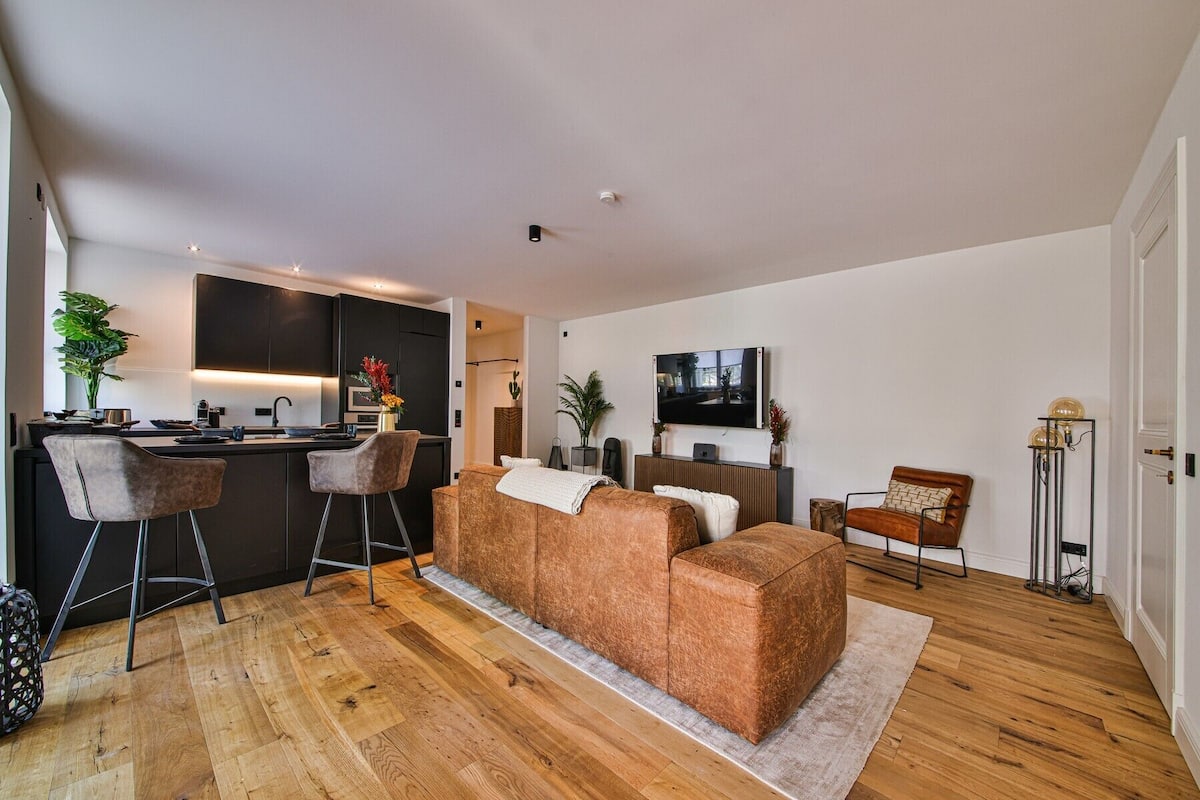 Ein modernes Wohnzimmer mit Sofa, Fernseher und Küchenzeile mit Bar.