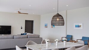 A modern living room with a sofa, a dining table with chairs, a television, and a ceiling fan. - Brand new Spacious 6 bedroom villa with stunning view, close to beach. (Lefkada)