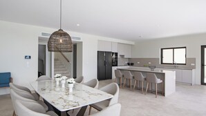 A modern kitchen with a central island, a dining area with a marble table, and a staircase leading to another level. - Brand new Spacious 6 bedroom villa with stunning view, close to beach. (Lefkada)