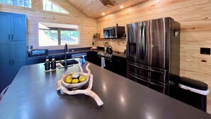 Una cocina moderna con paredes de madera, un refrigerador de acero inoxidable y una isla central con un cuenco de limones.