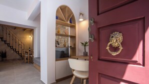 Un intérieur moderne avec un escalier, un coin repas et une porte rouge agrémentée d’une poignée décorative.