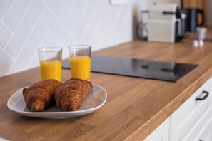 A breakfast setting with croissants on a plate and two glasses of orange juice on a wooden table. - Rodos Old Town Authentic Stone House (Rhodes)