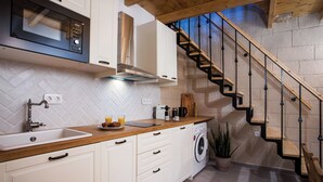 Une cuisine moderne dotée d’un plan de travail en bois, de meubles blancs, d’un four à micro-ondes encastré et d’un lave-linge.