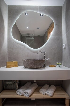 A bathroom with a large, round, stone sink, a wooden soap dish, and neatly folded towels on a shelf. - Rodos Old Town Authentic Stone House (Rhodes)