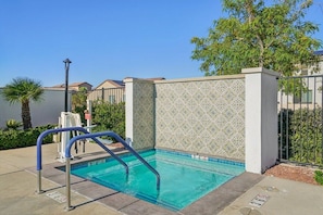 Ein Swimmingpool mit einer beplasterten Wand, einer Metallleiter und klarem, blauem Wasser.