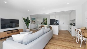Ein modernes Wohnzimmer mit grauem Sofa, Holzboden und einem Flachbildfernseher.