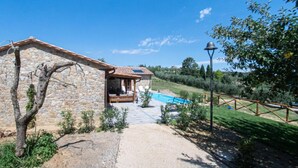 Un edificio de piedra con terraza de madera y piscina.