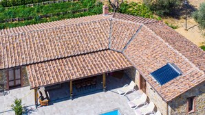 Un área de piscina en la azotea con una piscina rectangular, sillas de descanso y un patio cubierto con mobiliario exterior.
