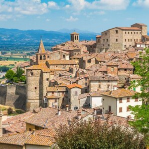A historic town with stone buildings, a prominent church with a bell tower, and a fortified wall. - Villa Il Melograno in Parrano (Parrano)
