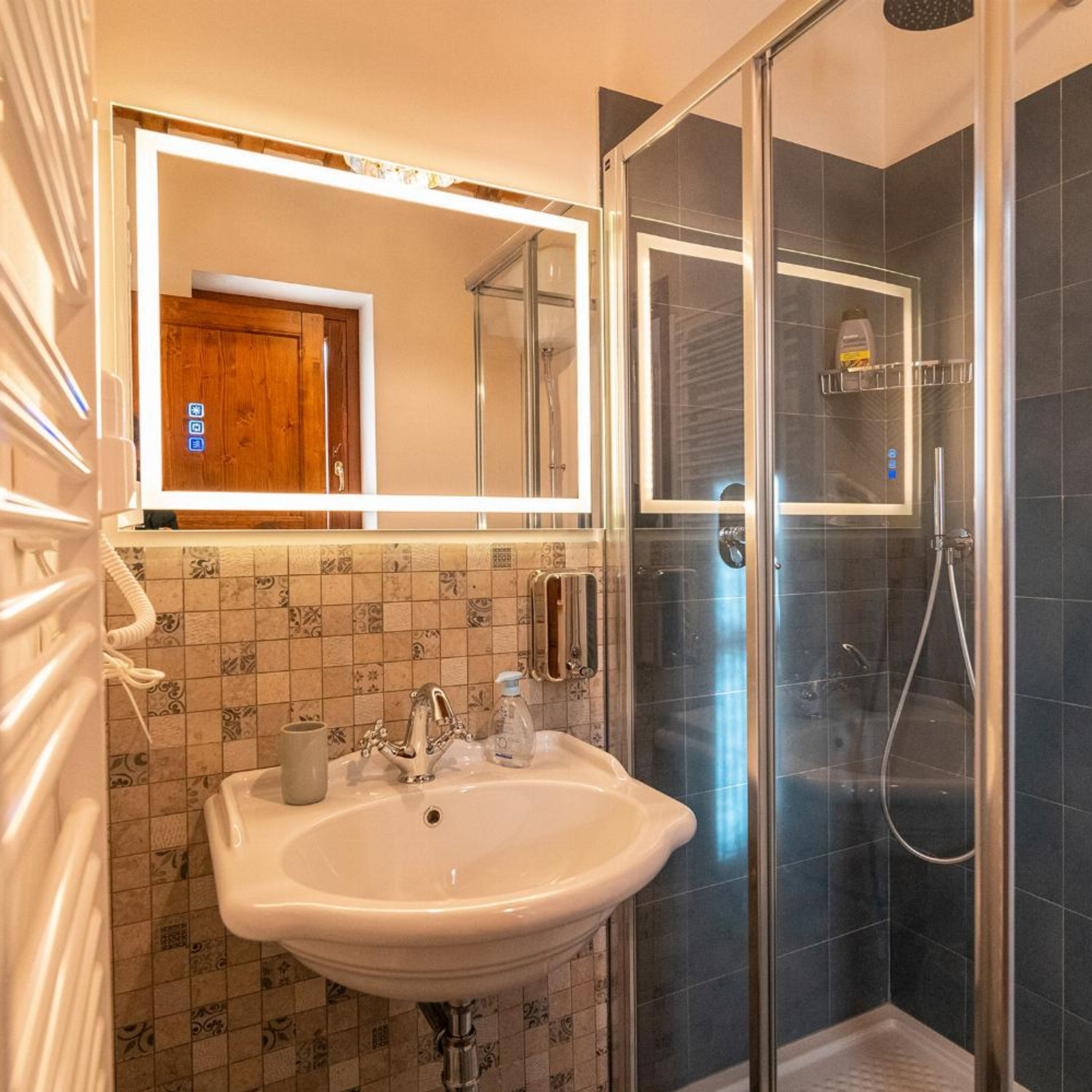 Un baño con lavabo, espejo y ducha.