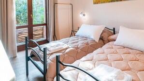 Un dormitorio con cama, ventana, un cuadro y una lámpara de techo.