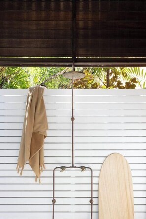 Relax in this serene space with a view of lush greenery outside, featuring a comfortable bed and a convenient towel rack.