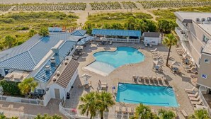 Un resort con una piscina grande, diverse zone relax e vista sulla spiaggia.