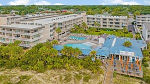 Un resort con diversi edifici, una piscina e una spiaggia attrezzata con lettini.