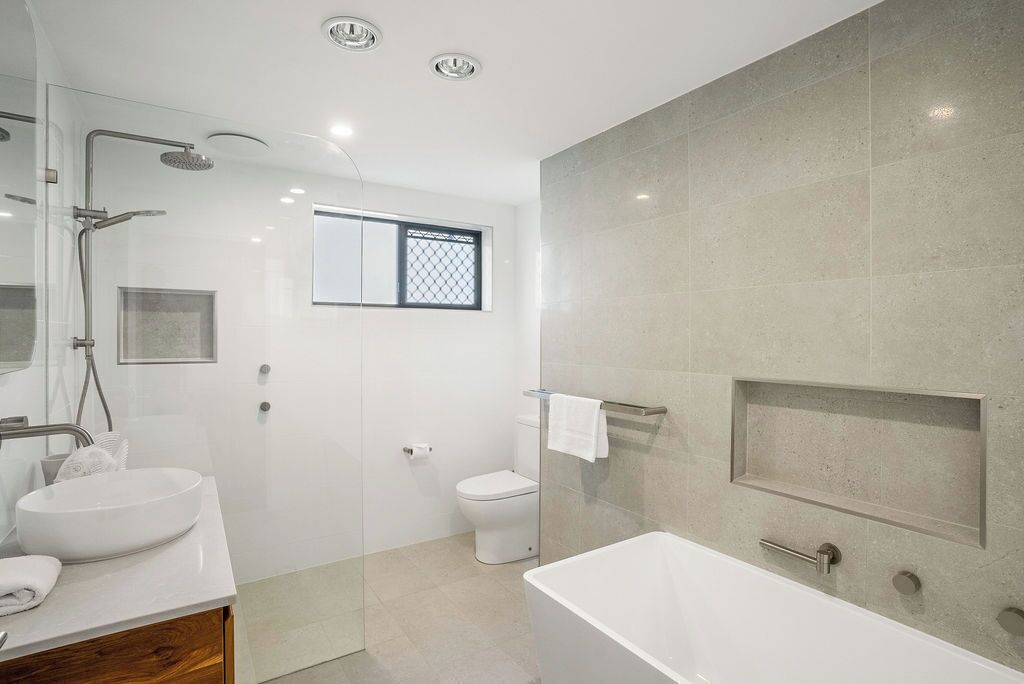 A modern bathroom with a glass-enclosed shower, a freestanding bathtub, a toilet, and a sink with a mirror.