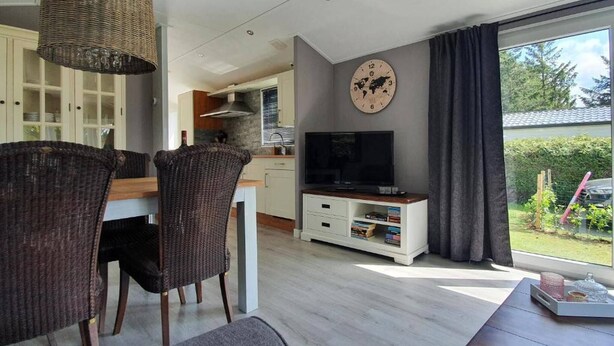 Et moderne køkken med spiseplads, et fjernsyn og et stort vindue.