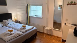 A bedroom with a bed, bedside tables, a window, a mirror, a radiator, and a small stool. - Paloma Chalet with Sauna - Relaxing Nature Escape by Lauwersmeer Park (Anjum)