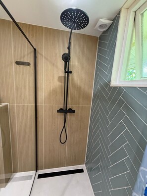 A shower with a handheld showerhead, a control panel, and a window with a view of greenery. - Paloma Chalet with Sauna - Relaxing Nature Escape by Lauwersmeer Park (Anjum)