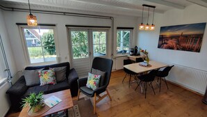 Une pièce comprenant un canapé, une table à manger, des chaises, une machine à café et un tableau accroché au mur.
