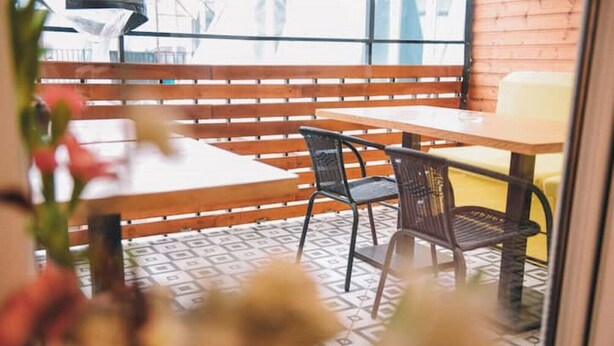 Een terras met een houten bank, een tafel en stoelen.