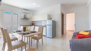 A modern kitchen with white cabinets, a grey refrigerator, and a dining area with a table and chairs. - 3952 Trilo di Annahouse by Barbarhouse (Porto Cesareo)