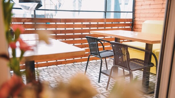 A café with wooden benches and tables, a patterned floor, and a view through a window. - Rooftop Grey Apartment at Rustaveli Avenue (T'bilisi)