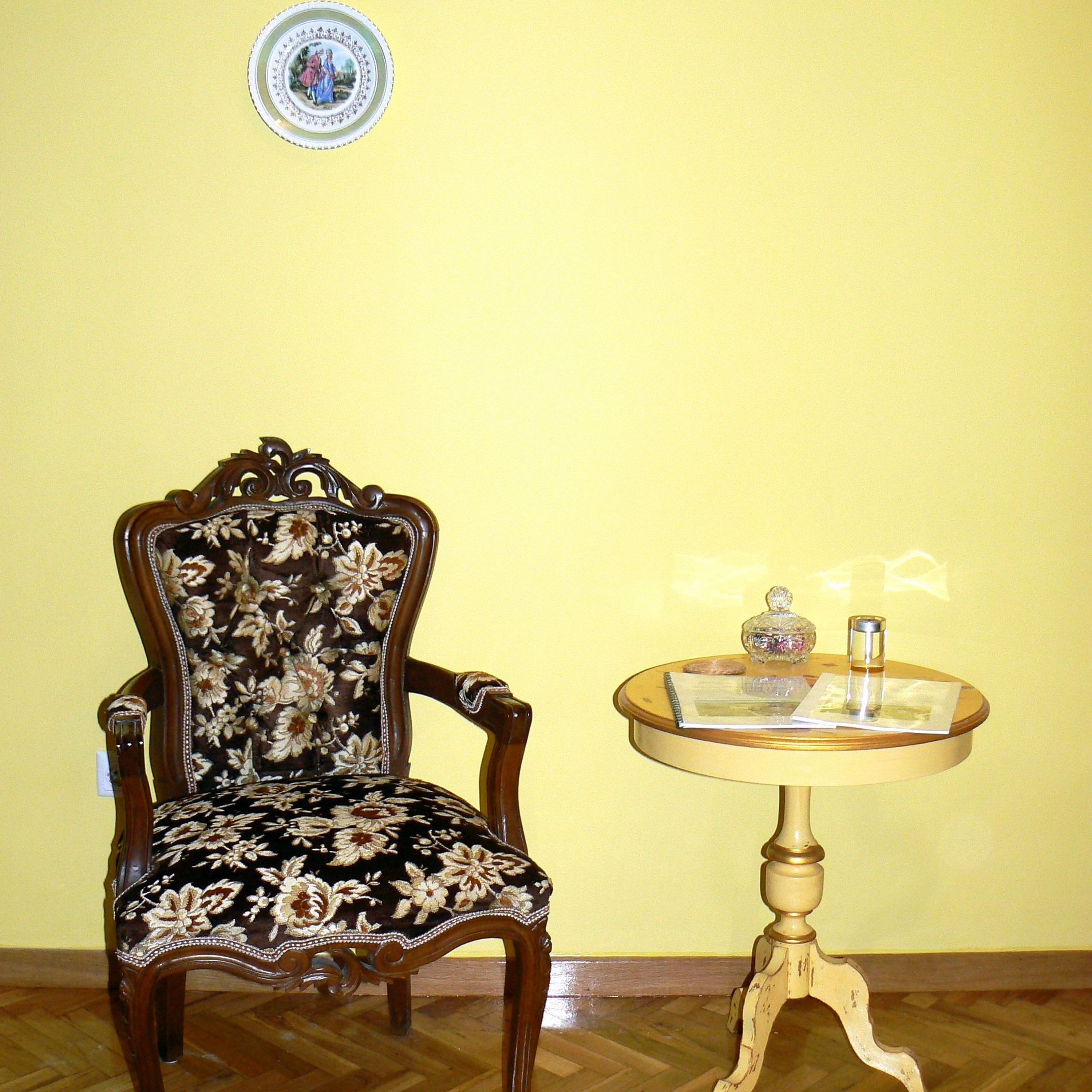 A chair with floral upholstery and a round table with a glass top and a decorative item on it.