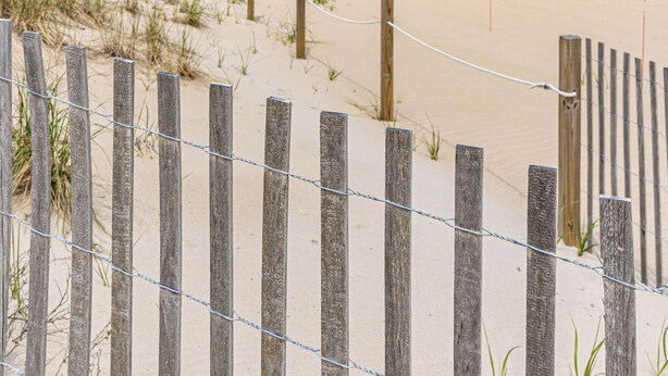 A beach with a wooden fence and rope barrier, sandy beach, and ocean in the background. - Ocean and Bay view luxury condo with balcony  (Ocean City)