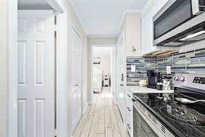 Una cocina estrecha con microondas, estufa y salpicadero de azulejos.