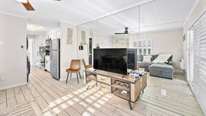 A modern living room with a TV, wooden entertainment unit, and a ceiling fan. - Ocean and Bay view luxury condo with balcony  (Ocean City)