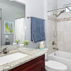 A bathroom with a granite countertop, a white toilet, a shower with a glass door, and a towel rack with a blue towel. - Phoenix Quite Area Pool and Great Water few (Cape Coral)