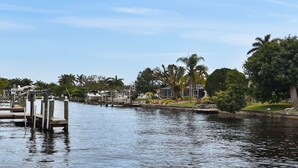Un port de plaisance avec des bateaux amarrés, un ciel dégagé et une végétation luxuriante tout autour.