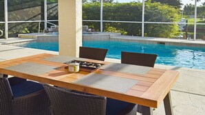 An outdoor dining area with a pool in the background. - Su Casa - XXL Pool Area Pool Spa 3 Bedroom 2 Bath (Cape Coral)