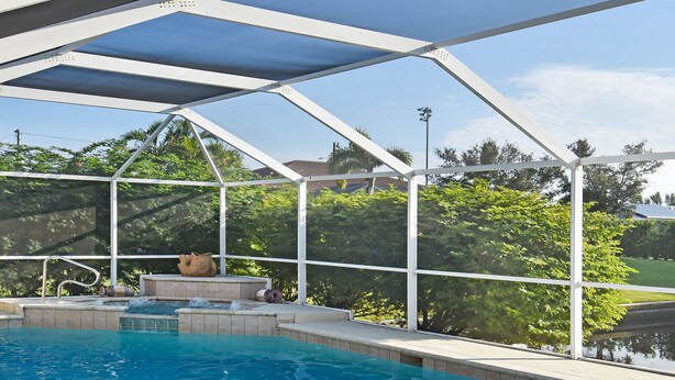 A swimming pool with a glass enclosure, surrounded by a tiled deck and a covered area with a built-in hot tub. - Su Casa - XXL Pool Area Pool Spa 3 Bedroom 2 Bath (Cape Coral)