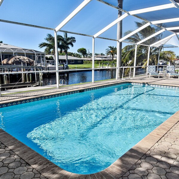 A swimming pool with a clear blue water, surrounded by a covered area with lounge chairs. - Boaters Dream S Terr Pool Yacht Club Boating (Cape Coral)