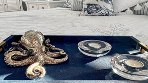 Une chambre à coucher avec un lit, un plateau contenant des objets décoratifs et une fenêtre avec des stores.