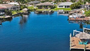 A marina with boats docked, a swimming pool, and surrounding houses.