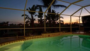 A swimming pool with a tiled edge, surrounded by a glass enclosure with a metal frame.