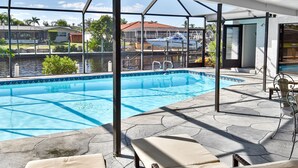 A pool area with lounge chairs and a view of the water. - Belle Paradise - 3 3 Pool Boating Oasis of Calm (Cape Coral)