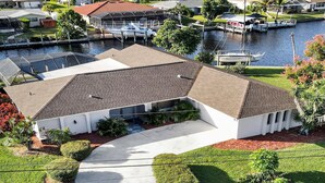 A two-story house with a covered patio, a driveway, and a view of a marina with boats. - Belle Paradise - 3 3 Pool Boating Oasis of Calm (Cape Coral)