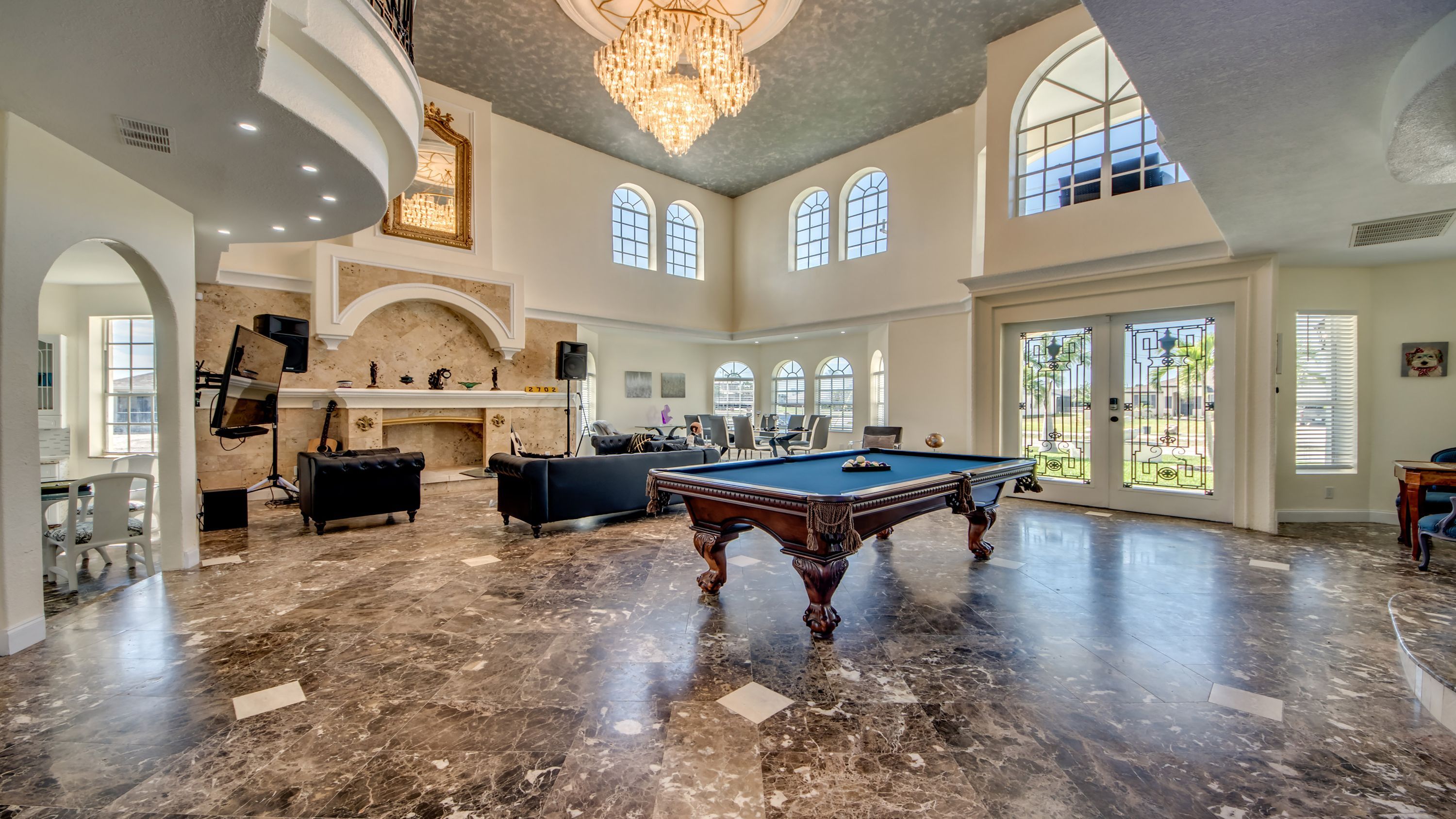 Une pièce spacieuse avec une table de billard, une cheminée et de grandes fenêtres.