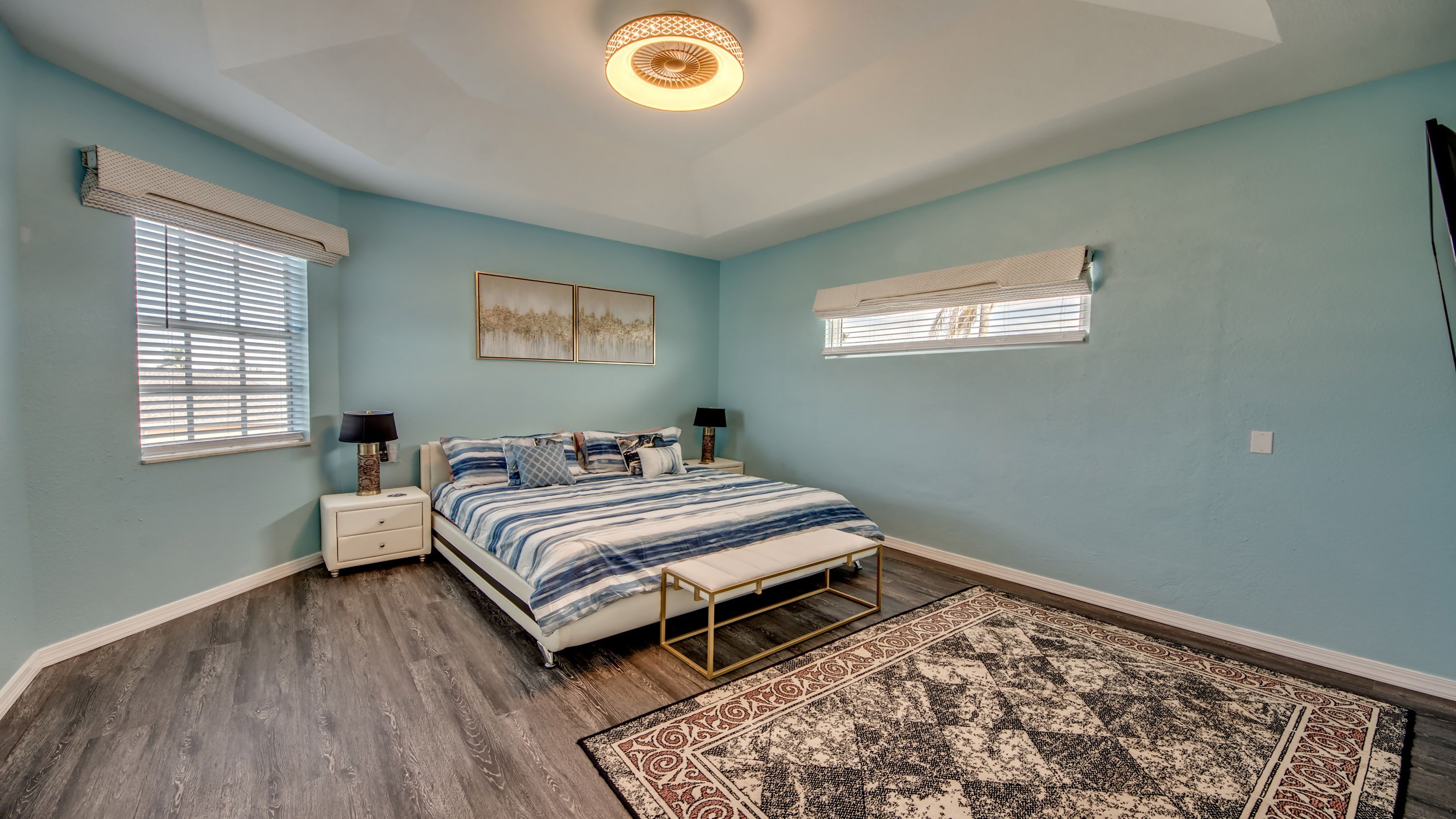 Une chambre à coucher avec un lit, des tables de chevet, un tapis et un luminaire au plafond.